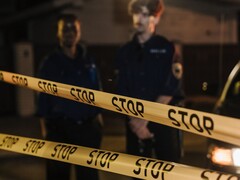 Due agenti di polizia in piedi di notte dietro un nastro giallo con la scritta Stop