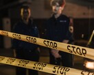 Due agenti di polizia in piedi di notte dietro un nastro giallo con la scritta Stop