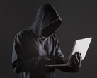 Un hacker incappucciato che utilizza un computer portatile su uno sfondo scuro.