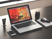 MacBook Pro su una scrivania scura accanto a uno smartphone, un paio di occhiali e un quaderno