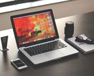MacBook Pro su una scrivania scura accanto a uno smartphone, un paio di occhiali e un quaderno