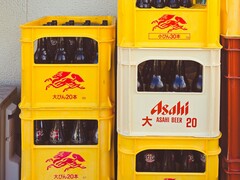 Casse di plastica gialle e bianche impilate e riempite di bottiglie di birra Asahi, con testo giapponese e logo rosso. (Fonte immagine: Foto di Alazne Lazcano via Pexels)