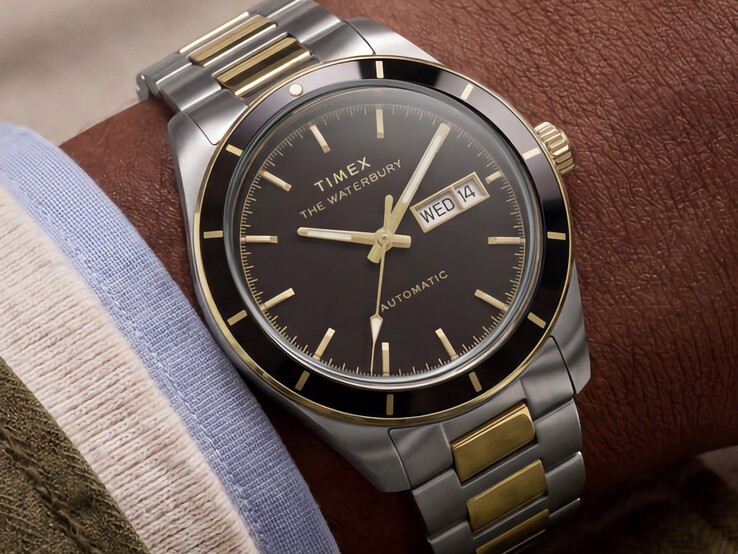 Orologio Timex Waterbury Heritage Automatic bicolore con quadrante nero indossato al polso, che mostra il datario con indicazione del giorno e dettagli dorati.