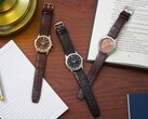 Tre orologi Citizen Rolan disposti su una scrivania di legno accanto a un taccuino, una penna, una lampada e un libro aperto, tra cui il modello AW2110-14Z con quadrante color salmone.