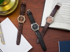 Tre orologi Citizen Rolan disposti su una scrivania di legno accanto a un taccuino, una penna, una lampada e un libro aperto, tra cui il modello AW2110-14Z con quadrante color salmone.