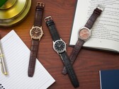 Tre orologi Citizen Rolan disposti su una scrivania di legno accanto a un taccuino, una penna, una lampada e un libro aperto, tra cui il modello AW2110-14Z con quadrante color salmone.