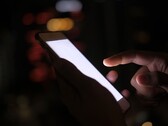 Mano che regge uno smartphone con lo schermo illuminato al buio