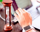 Clessidra accanto a una mano sulla tastiera di un computer portatile
