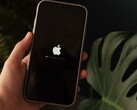 Una mano regge un iPhone; sullo schermo sono visibili il logo Apple e una barra di avanzamento.