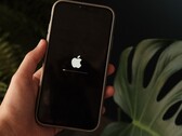 Una mano regge un iPhone; sullo schermo sono visibili il logo Apple e una barra di avanzamento.