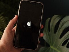 Una mano regge un iPhone; sullo schermo sono visibili il logo Apple e una barra di avanzamento.