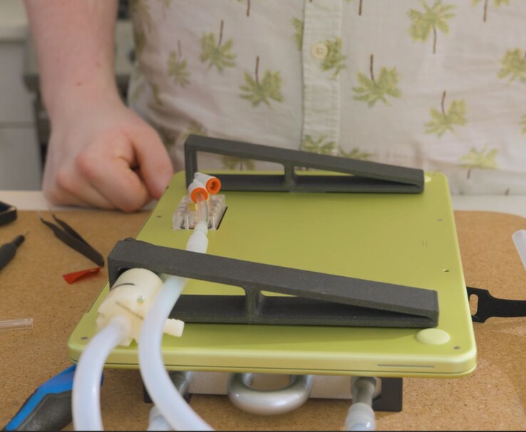 MacBook Neo modificato con pompa esterna e configurazione dei tubi per il raffreddamento a liquido fai da te