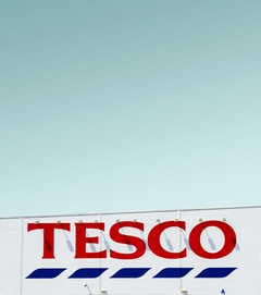 L'insegna esterna di Tesco fotografata contro un cielo limpido (Fonte: Simone Hutsch via Unsplash)