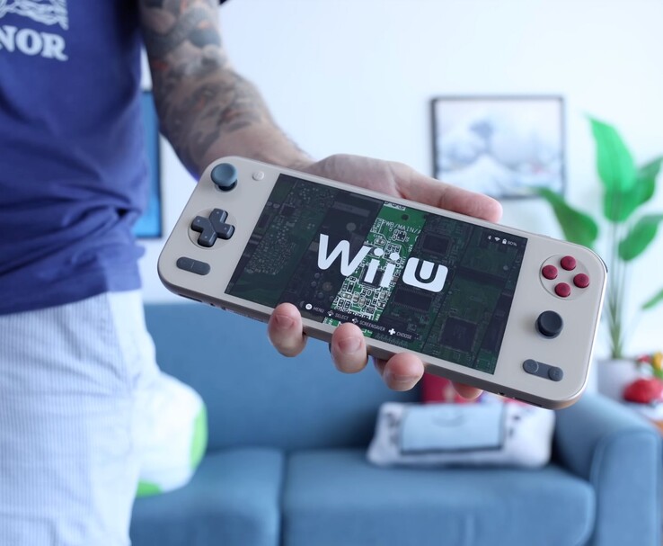 Russ di Retro Game Corps con in mano la console portatile Ayaneo Pocket S2 che esegue un emulatore Wii U, con il dispositivo mostrato in primo piano in un salotto. (Fonte: Retro Game Corps)
