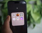 Una mano regge uno smartphone su cui è visibile una cartella denominata «AI» contenente app quali Gemini, ChatGPT e Claude