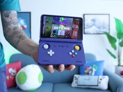 Russ di Retro Game Corps con in mano la console di gioco portatile Retroid Pocket Flip 2 di colore viola, con lo schermo che visualizza un'interfaccia di emulazione di Sega Genesis. (Fonte: Retro Game Corps su YouTube)