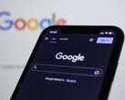 Smartphone che mostra la pagina di ricerca di Google davanti a uno schermo con il logo di Google