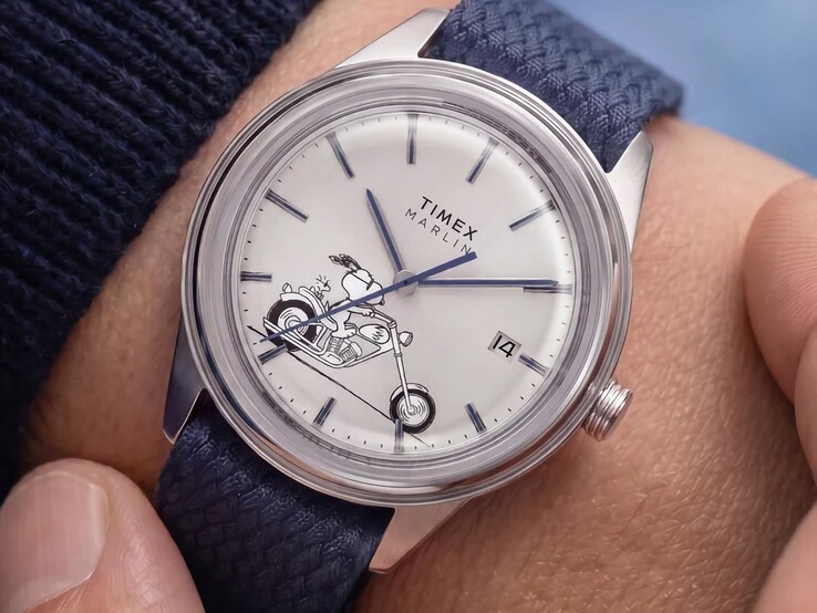 L’orologio Peanuts x Timex Marlin Jet Automatic Easy Rider indossato al polso, che raffigura Snoopy in sella a una motocicletta sul quadrante bianco-argento, con indici e lancette blu e un cinturino in tessuto intrecciato blu.