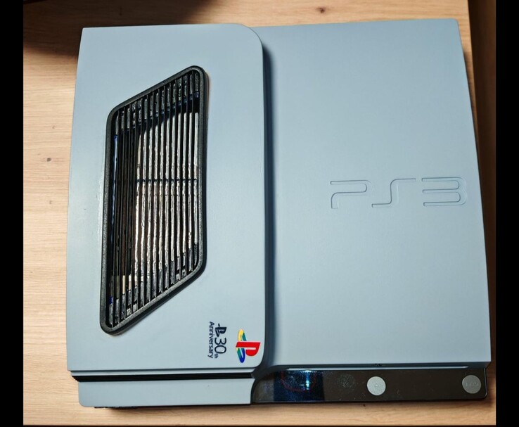 Vista dall'alto della PS3 Slim Pro personalizzata grigio-argento opaco con accenti neri, caratterizzata da una griglia di ventilazione e dal logo del 30° Anniversario di PlayStation sul case. (Fonte immagine: Fun-Equivalent-7785 via Reddit / r/PS3)