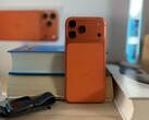 Apple l'iPhone 17 Air in finitura arancione mostra il design posteriore e il modulo della fotocamera posizionato su libri impilati