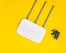 Router Wi-Fi bianco con tre antenne e un alimentatore su sfondo giallo