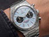 Primo piano del cronografo Timex Q Timex Continental TW2Y92400 indossato al polso, caratterizzato da un quadrante radiale in stile CD color blu ghiaccio, contatori neri, lunetta tachimetrica argentata e bracciale integrato in acciaio inossidabile.