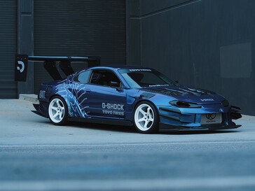 Un’auto da drift blu con grafiche G-Shock e Toyo Tires parcheggiata all’esterno di un capannone industriale.