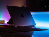 Un MacBook semiaperto in una stanza buia, con la luce che filtra dalla fessura e si riversa sulla scrivania