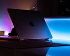 Un MacBook semiaperto in una stanza buia, con la luce che filtra dalla fessura e si riversa sulla scrivania