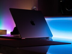 Un MacBook semiaperto in una stanza buia, con la luce che filtra dalla fessura e si riversa sulla scrivania