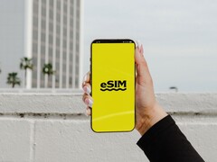 Una mano che regge uno smartphone con la parola «eSIM» scritta a caratteri grandi su uno schermo giallo.