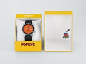 Orologio automatico Seiko 5 Sports x Popeye HDB013 con quadrante arancione, accanto alla sua confezione gialla in edizione limitata.