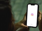 Donna che tiene uno smartphone con entrambe le mani; sul display è visibile la schermata iniziale di Instagram