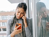 Una donna guarda il proprio smartphone con espressione seria