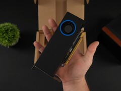 Una persona che tiene in mano la GPU per workstation a basso profilo Intel Arc Pro B50 con un raffreddatore di tipo blower, raffigurata contro la sua scatola di imballaggio. (Fonte: ETA Prime via YouTube)