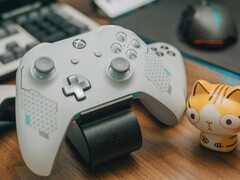 Un controller Xbox bianco appoggiato su una scrivania di legno accanto a una statuetta di gatto (Fonte immagine: FOX ^.ᆽ.^= ∫ via Pexels)