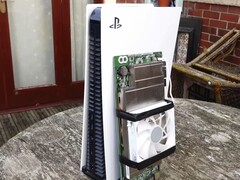 Una console PlayStation 5 posizionata accanto a una scheda AMD BC250 personalizzata, montata con un dissipatore e una ventola di raffreddamento. (Fonte: Budget-Builds Official via YouTube)